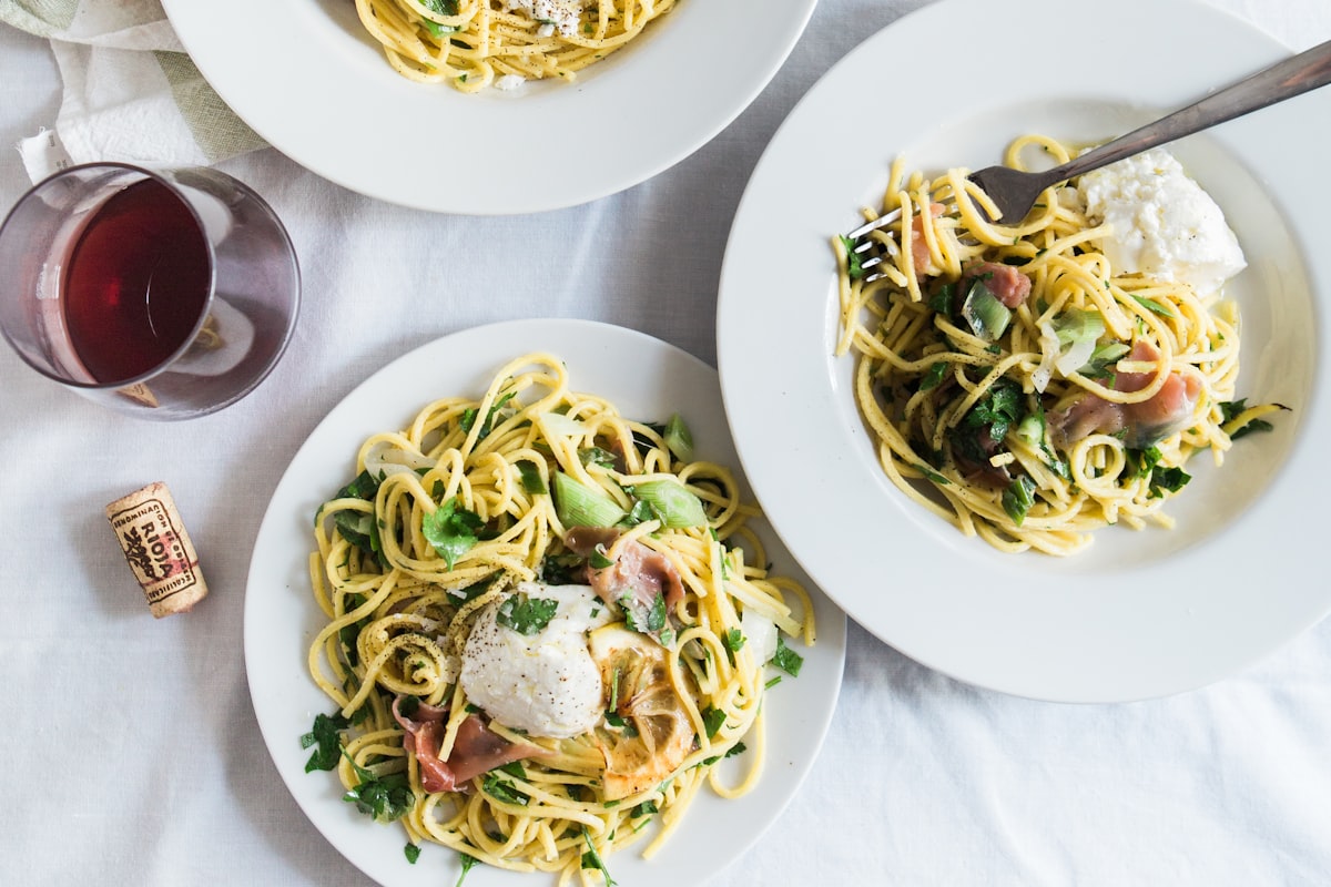 Shared plates of fresh Italian pasta with red wine, ideal for a pre-theatre dinner near Curve Theatre