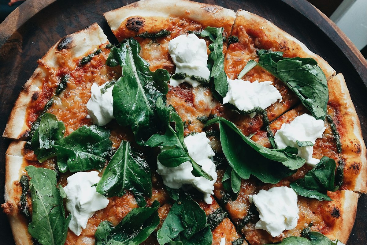 Stone-baked pizza topped with burrata and rocket, a vegetarian option at Merchant of Venice