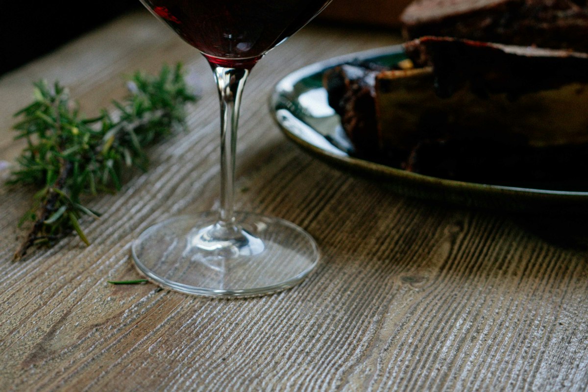 Red wine being poured alongside a plated dish, showing the food pairing element of wine tasting at Merchant of Venice